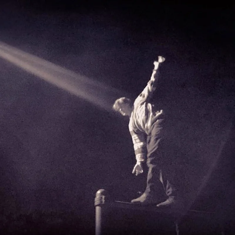 James balancing on a rail at night, lit by a single beam
